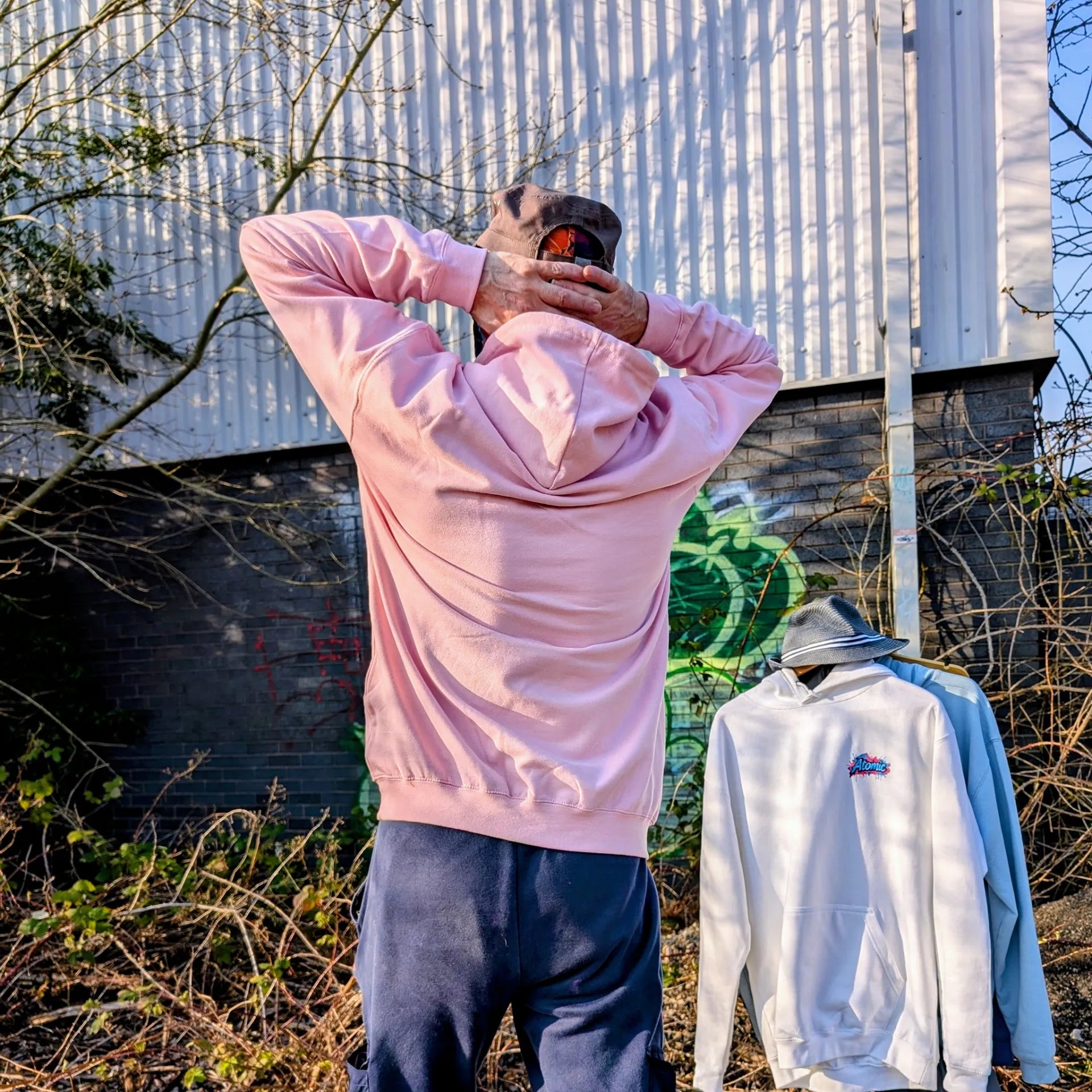 The Sun Walker wearing a Al Hazzati Atomic New Wave baby pink hoodie in Manchester graffiti location