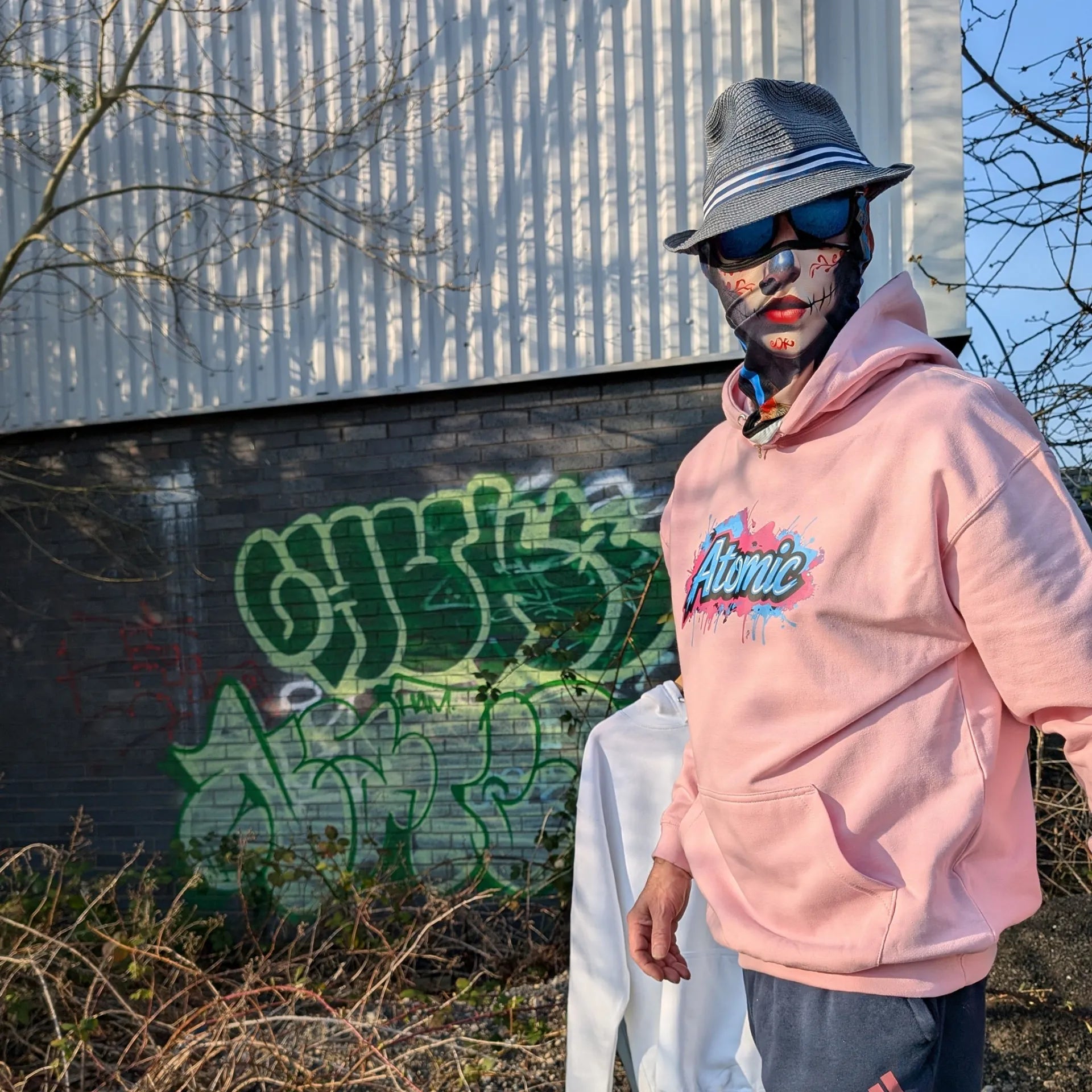 The Sun Walker wearing a Al Hazzati Atomic New Wave baby pink hoodie in Manchester graffiti location